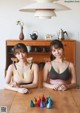 Two young women sitting at a wooden table.