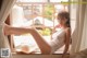 A woman in a white lingerie sitting on a window sill.