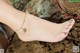 A woman wearing a gold anklet with a bird on it.