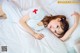 A woman laying on a bed with a red cross on her shirt.