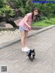 A woman walking a small dog on a leash.