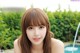 A woman with long brown hair and bangs posing by a pool.