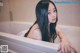 A woman with long black hair sitting in a bathtub.