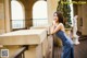 A woman in a blue dress leaning against a railing.