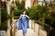 A woman in a blue dress standing on a bridge.